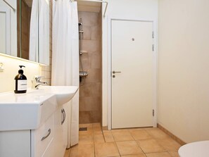 Une salle de bain avec un lavabo blanc, une douche et une porte sur laquelle est apposée une pancarte indiquant « accès interdit ».
