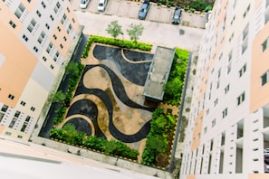 A high-rise building with a rooftop garden featuring winding pathways and greenery. - Elegant And Comfortable Studio At Urbantown Serpong Apartment (South Tangerang)