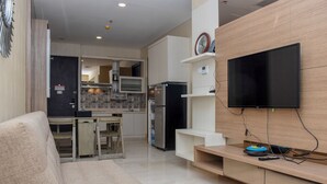 A modern living room with a flat-screen TV, a sofa, and a kitchen area in the background. - Exclusive And Comfort 2Br Apartment At Sudirman Suites (Jakarta)