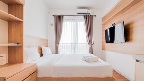 A modern hotel room with a wooden bed, built-in wardrobe, and a flat-screen TV mounted on the wall. - Nice And Comfortable Studio Apartment At Sky House Bsd (Pagedangan)