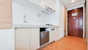 A modern kitchen with white cabinets, a stainless steel refrigerator, and a built-in oven. - Nice And Comfortable Studio Apartment At Sky House Bsd (Pagedangan)