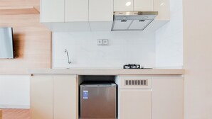 A compact kitchen with a built-in refrigerator, a stove, and a sink. - Nice And Comfortable Studio Apartment At Sky House Bsd (Pagedangan)
