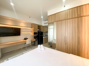 Una moderna camera d'albergo con televisione a schermo piatto, scrivania, sedia, letto e armadio.