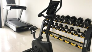 A gym with a treadmill, an elliptical, and a rack of dumbbells.