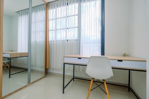 A room with two desks, a chair, and a large mirror. - Minimalist Studio Room At Evenciio Margonda Apartment (Depok)