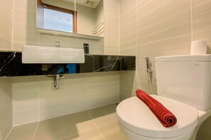 Ein Badezimmer mit einer weißen Toilette, einem Waschbecken mit schwarzer Arbeitsplatte und einem Spiegel darüber.