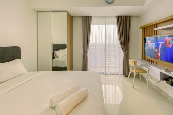 Ein Hotelzimmer mit Bett, Schreibtisch mit Stuhl, Fernseher und Kleiderschrank.