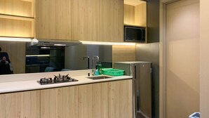 Eine moderne Küche mit Holzausstattung, einem Edelstahlkühlschrank und einer eingebauten Mikrowelle.
