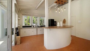 A spacious kitchen with white cabinets, a central island, and a hanging light fixture.