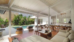 A spacious indoor area with a pool, seating, and a dining area.