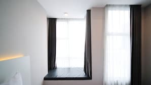 Une chambre d’hôtel dotée d’une grande fenêtre, d’une banquette intégrée et d’un luminaire au plafond.