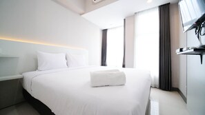 Ein modernes Hotelzimmer mit einem großen Bett, einem flachbildfernseher an der Wand und einem Fenster mit Vorhängen.