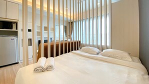 Een hotelkamer met een groot bed, een bureau, een kledingkast en een koelkast.