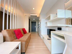A modern living room with a sofa, TV, and built-in shelves. - Elegant And Comfortable Studio At Tamansari The Hive Apartment (Jakarta)