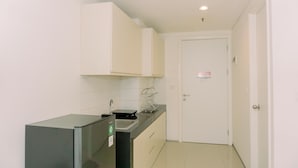 Een compacte, moderne keuken met een koelkast, spoelbak en kastjes.