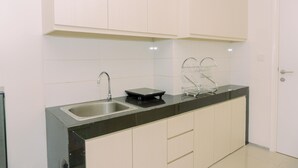 Een keuken met witte kastjes, een zwart aanrecht, een spoelbak en een afwasschaal.