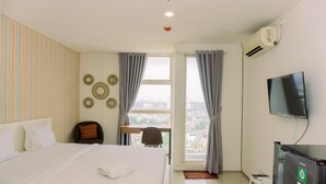 Een hotelkamer met een bed, een bureau, een stoel, een televisie en een raam met gordijnen.