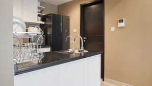 A modern kitchen with a black countertop, white cabinets, and a double sink. - Comfort Stay 1Br At Branz Bsd City Apartment (Pagedangan)