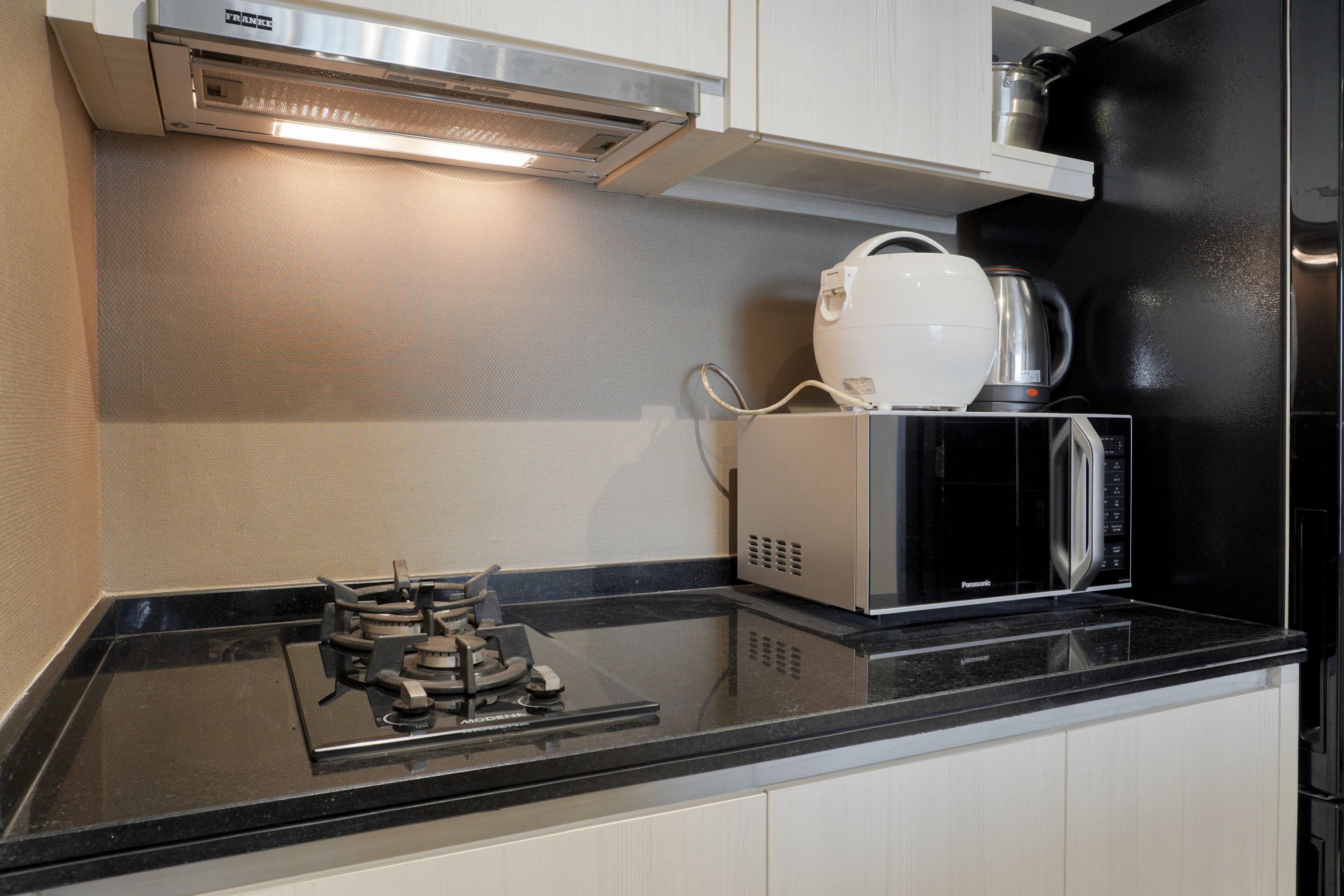 Una cocina con encimera negra, estufa a gas, microondas y hervidor.