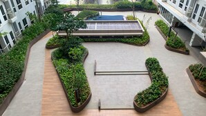 Un jardín en la azotea con piscina, rodeado de vegetación y arquitectura moderna.