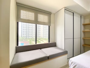 Enjoy a view of the city from the large window, with a bench and wardrobe for added comfort.