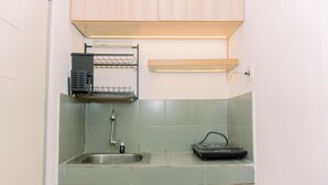 A compact kitchen with a sink, a small countertop, and a built-in oven. - Comfort 2Br At 22Nd Floor Menara Kebon Jeruk Apartment (Jakarta)