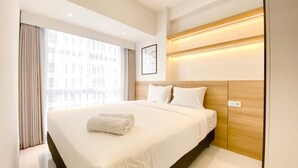 A modern hotel room with a large bed, a wooden headboard, a window with curtains, and a framed picture on the wall. - Nice And Comfortable 2Br At 20Th Floor Tokyo Riverside Apartment (Teluknaga)