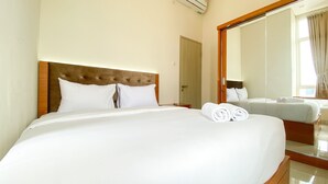 Una camera d'albergo con un grande letto, una testiera in legno e uno specchio che riflette l'ambiente.