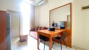 Una camera d'albergo con una scrivania in legno, un divano, una televisione e un condizionatore d'aria.