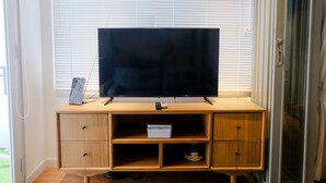 Un mueble de televisión de madera con un televisor de pantalla plana, un control remoto y una pequeña caja blanca.