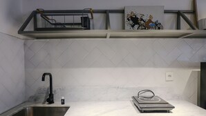Una cocina con un lavamanos de acero inoxidable, una encimera y una placa de inducción integrada.