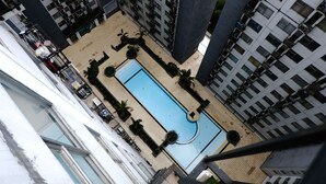 Un edificio de gran altura con un patio central que cuenta con una piscina, rodeado de follaje y plantas en macetas.
