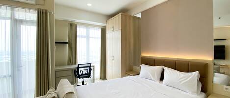 Una habitación de hotel con una cama grande, un escritorio, una silla y un armario.