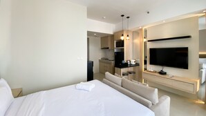 Een moderne hotelkamer met een groot bed, een bank, een flatscreen-tv, een kitchenette en een eettafel.