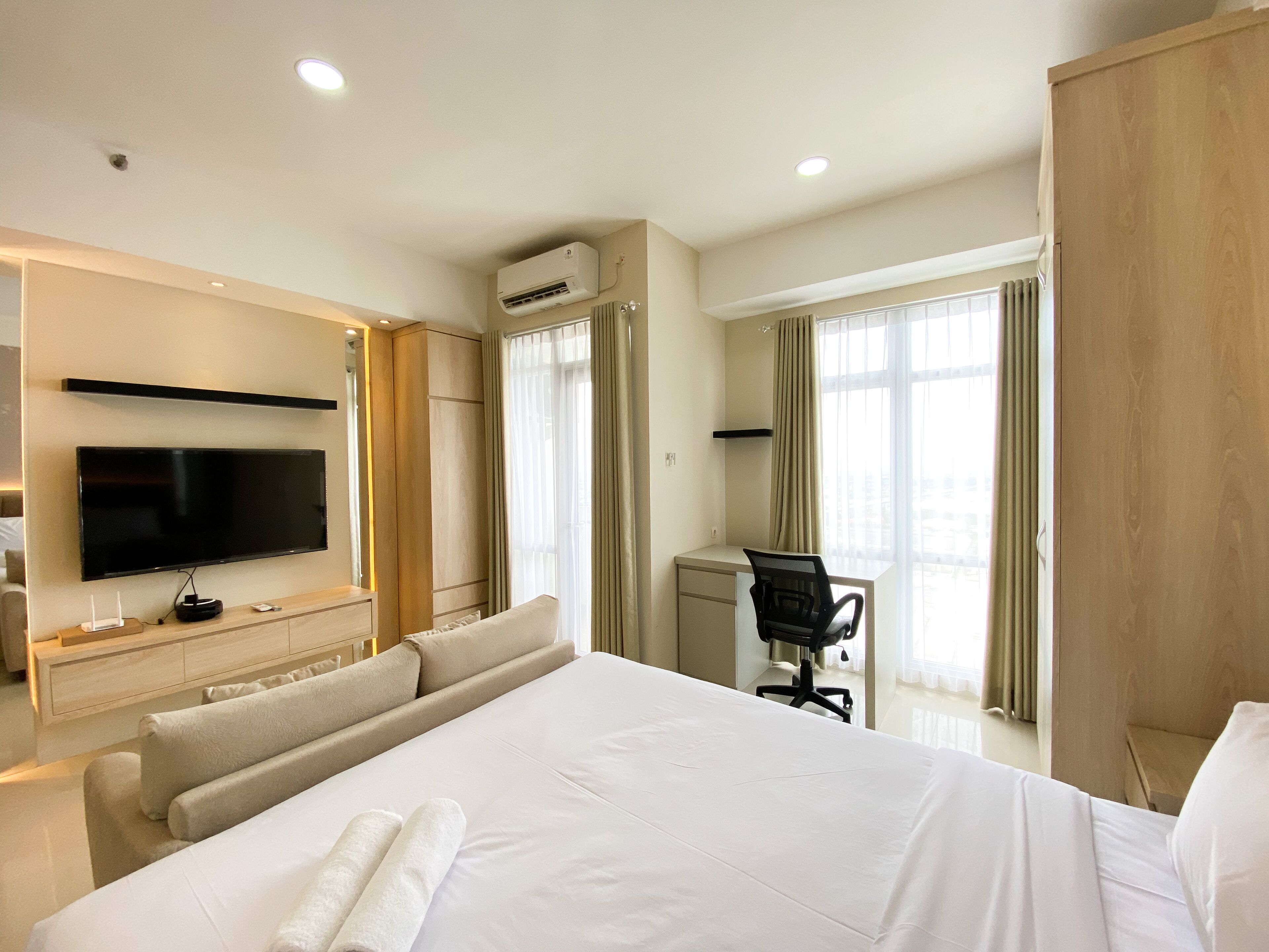 Une chambre d’hôtel avec un grand lit, un bureau, une chaise, une télévision et un appareil de climatisation.