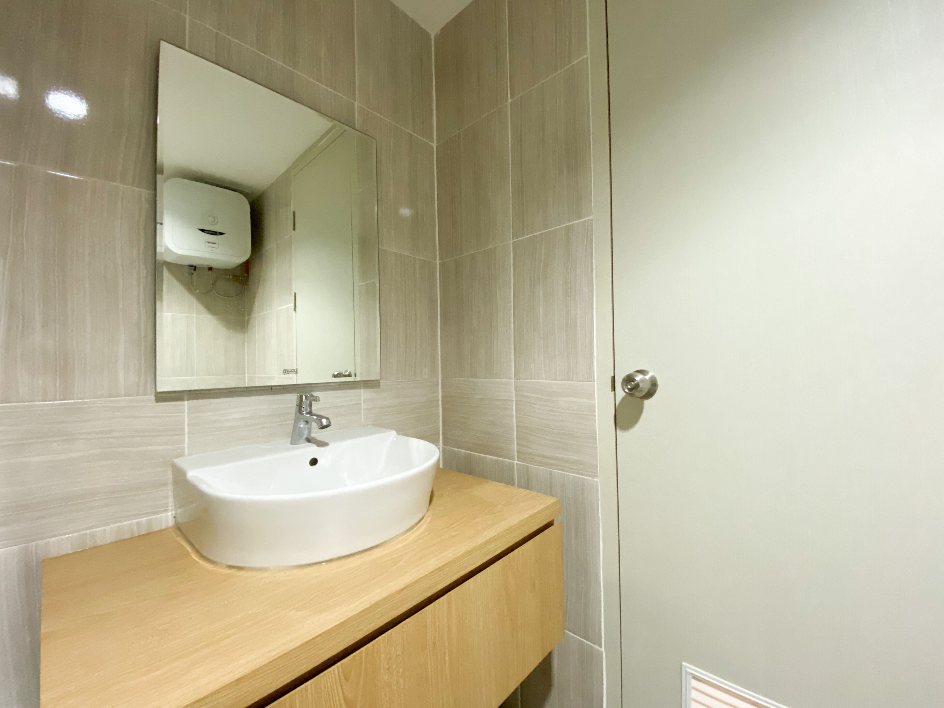 A bathroom with a white sink, a mirror, and a wooden vanity.
