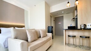 Een moderne hotelkamer met een bed, een slaapbank, een koffieapparaat en een minibars.