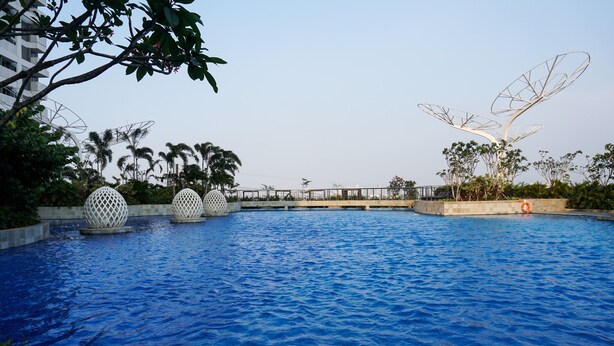 A swimming pool with decorative spherical structures and a bridge in the background. - Modern Classic Studio At West Vista Apartment (Jakarta)