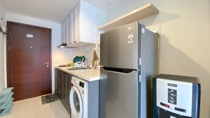A compact kitchen with a washing machine, a refrigerator, and a microwave. - Modern Classic Studio At West Vista Apartment (Jakarta)