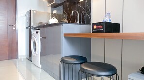 Une cuisine moderne dotée d’un lave-linge encastré, d’un évier avec un dosseret en marbre et d’un coin bar avec une bouteille d’eau.