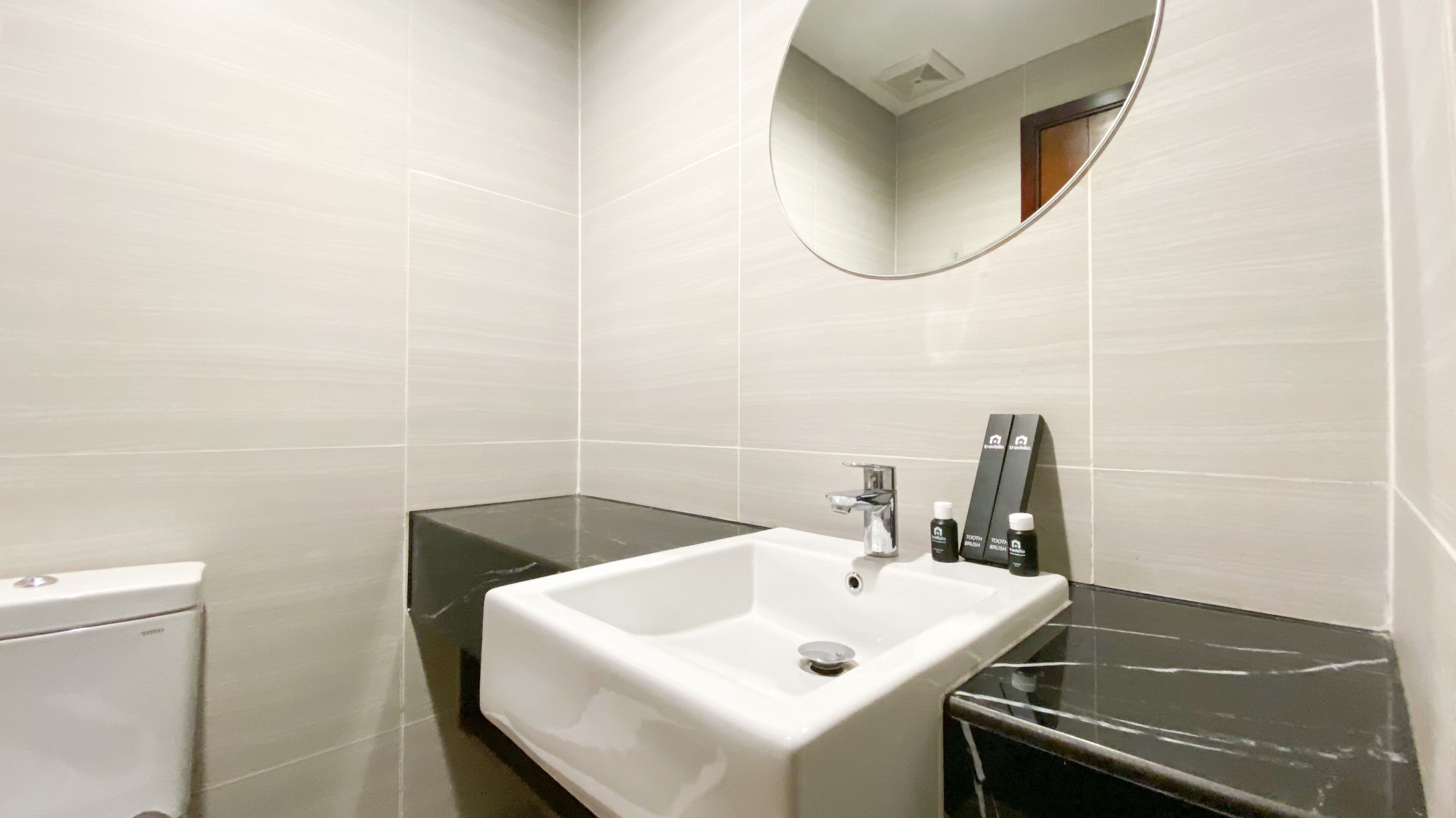 Une salle de bain avec un lavabo blanc, un miroir et des articles de toilette posés sur le comptoir.