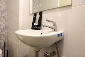A white bathroom sink with a modern faucet, a mirror above it, and a hand dryer to the right. - Comfy And Simply Studio Tokyo Riverside Pik 2 Apartment (Teluknaga)
