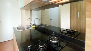 A modern kitchen with a gas stove, stainless steel sink, and a range hood. - Cozy Stay Studio Room At Springlake Summarecon Bekasi Apartment (Bekasi)