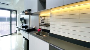 A modern kitchen with white cabinets, a stainless steel sink, and a tiled backsplash. - Cozy Stay Studio At Sayana Bekasi Apartment (Tarumajaya)