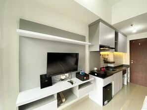A modern kitchen with a built-in TV, white cabinetry, and a small countertop. - Cozy Stay Studio At Sayana Bekasi Apartment (Tarumajaya)
