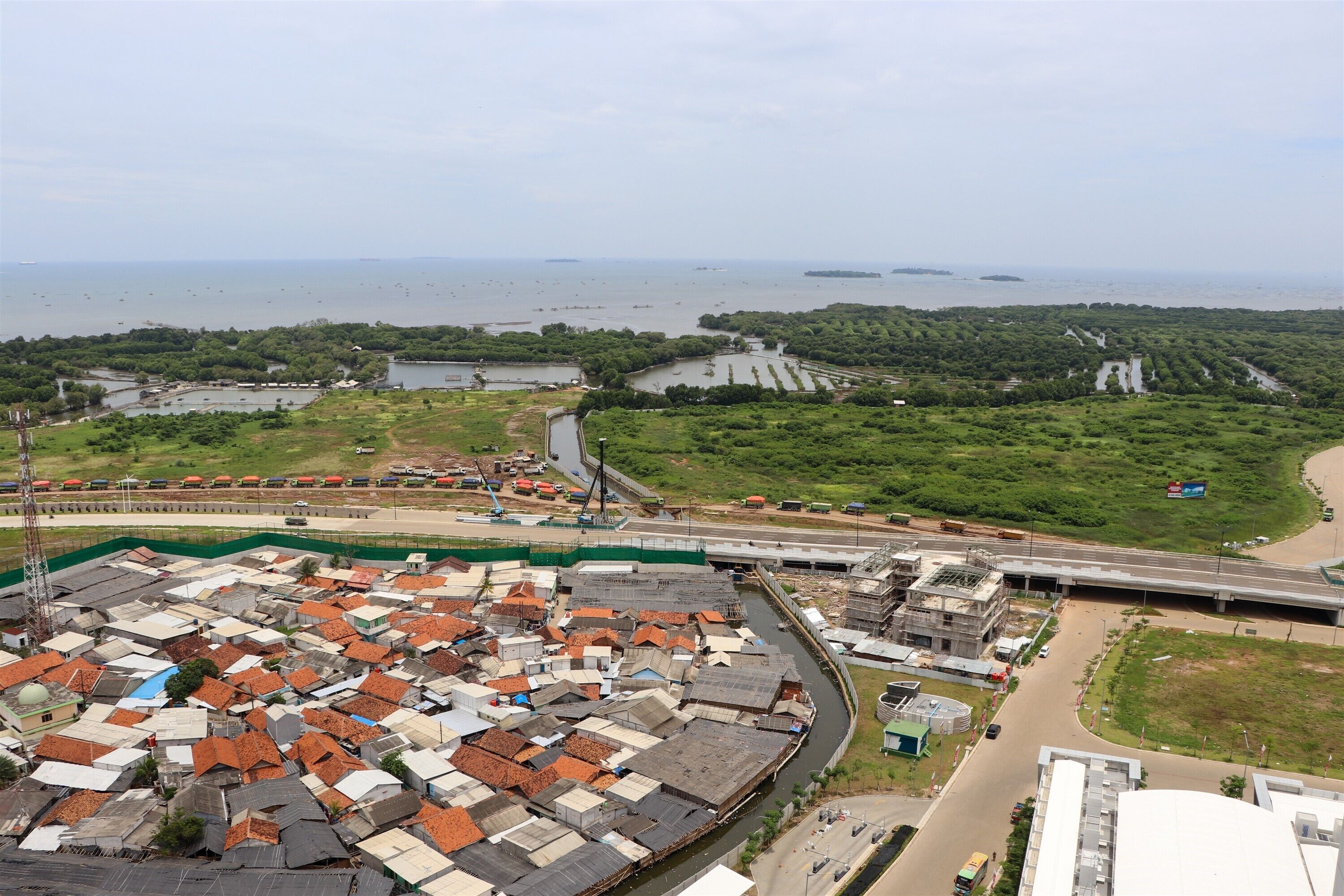 A coastal area with a mix of residential and commercial buildings, a highway, and a body of water.