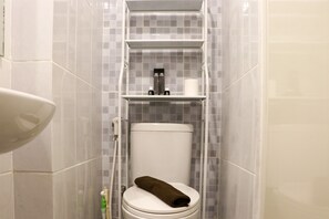 Ein Badezimmer mit Toilette, Ablagefläche für Toilettenartikel und Spiegel.