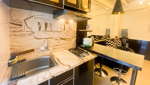 A modern kitchen with marble backsplash, stainless steel appliances, and a black bar counter. - Great Deal And Comfortable 2Br At Bassura City Apartment (Jakarta)