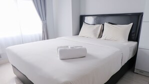 A neatly made bed with white linens and a folded towel on the bed. - Homey 1Br Apartment At Newton Residence Bandung (Bandung)