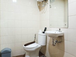 Et badeværelse med toilet, vask og spejl.